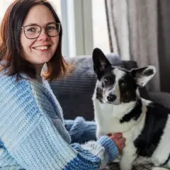 Kvinna med glasögon och en hund med finska hundnamn sitter i en soffa.