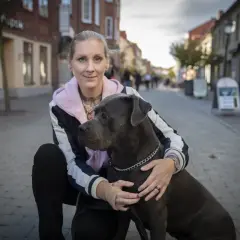 Kvinna med stor hund på kullerstensgata. En vacker hyllning till minne av hund.
