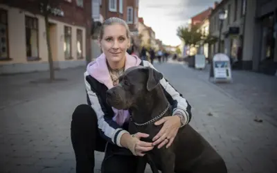 Kvinna med stor hund på kullerstensgata. En vacker hyllning till minne av hund.