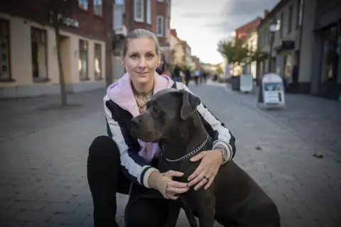 Kvinna med stor hund på kullerstensgata. En vacker hyllning till minne av hund.