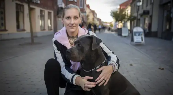 Kvinna med stor hund på kullerstensgata. En vacker hyllning till minne av hund.