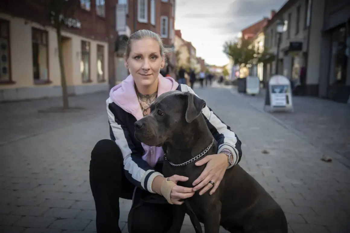 Kvinna med stor hund på kullerstensgata. En vacker hyllning till minne av hund.