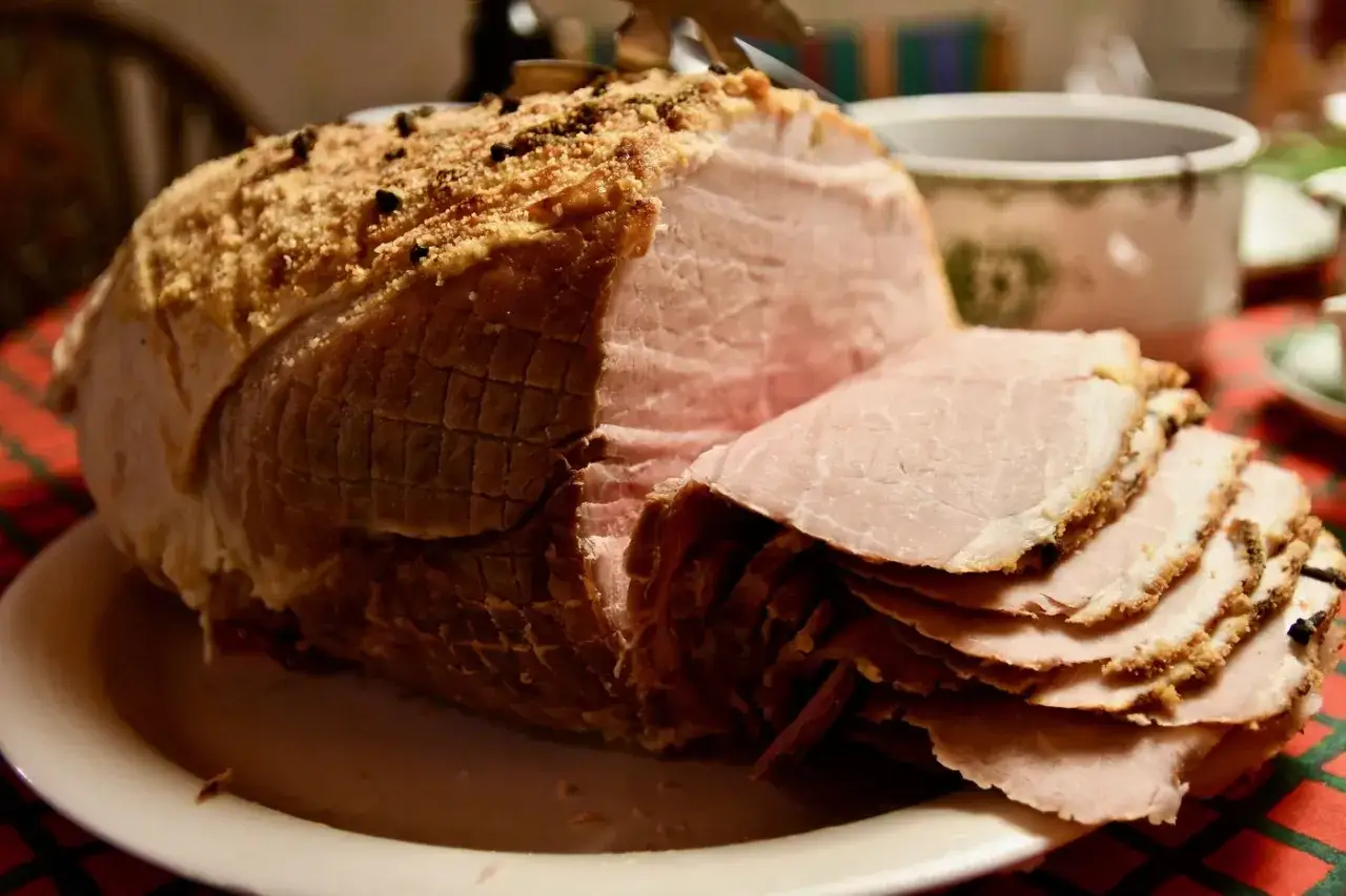 En saftig julskinka med krispig yta, perfekt f&ouml;r en hund att dr&ouml;mma om. Skivorna ligger staplade, redo att serveras.