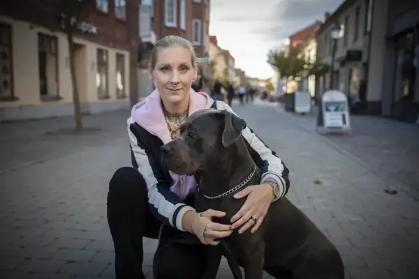 Kvinna med stor hund på kullerstensgata. En vacker hyllning till minne av hund.
